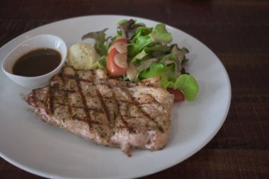 Beyaz tabakta servis edilen ızgara sebzeli biftek..