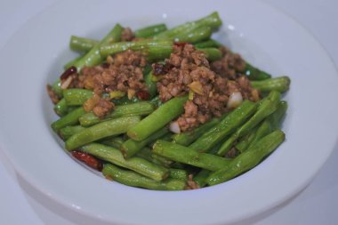 beyaz plaka üzerinde kıyma domuz ile doğranmış dize fasulye.