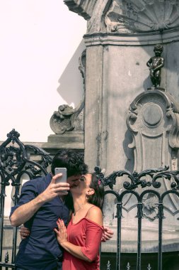 Brüksel, Belçika, 10 Haziran 2018. Bir erkek ve bir kadın öpücük ve bir heykelin bir selfie yapmak Manneken bi