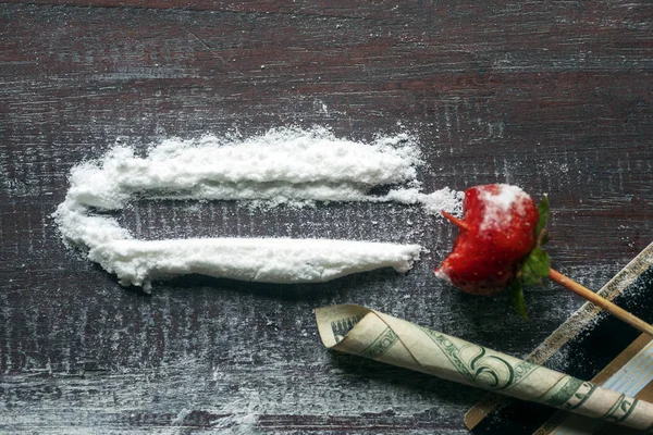 Cocaine on a wooden table, dollar bill twisted into a tube and a bank card.
