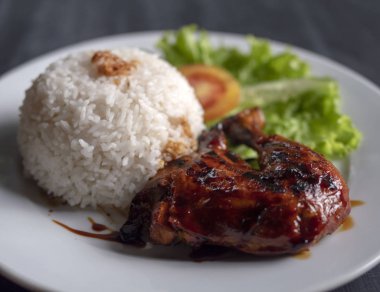 Tabak üzerinde pirinç ile ızgara tavuk bacağı