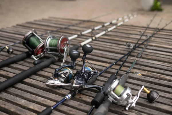 Cañas de pescar, cañas giratorias con hilo de pescar sobre un fondo de madera a la luz de la mañana. Pesca . — Foto de Stock