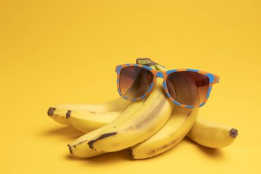 sarı bir arka plan üzerinde muz ve güneş gözlüğü