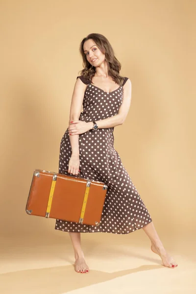 Dziewczyna w polka-dot sukienka z walizką retro. — Zdjęcie stockowe