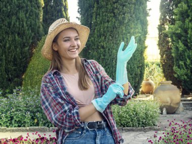 Genç kadın bahçıvan sabah güneşi ile aydınlatılmış bir bahçede çalışıyor