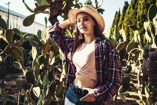 Mujer joven en un sombrero de paja sobre un fondo de cactus —  Fotos de Stock