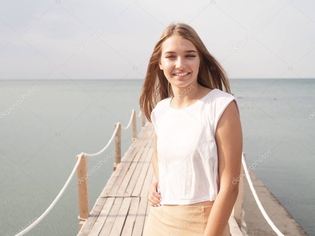 Girl on the pier with a bungalow on the background of the sea. 