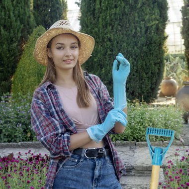 Genç kadın bahçıvan sabah güneşi ile aydınlatılmış bir bahçede çalışıyor