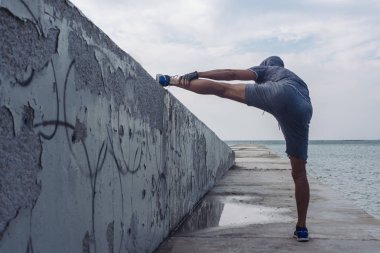 Erkek atlet deniz de bir parapet üzerinde uzanır
