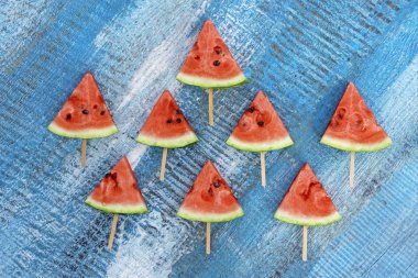 Mavi ahşap arka plan üzerinde karpuz üçgen dilimleri.