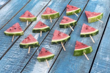 Mavi ahşap arka plan üzerinde karpuz üçgen dilimleri.
