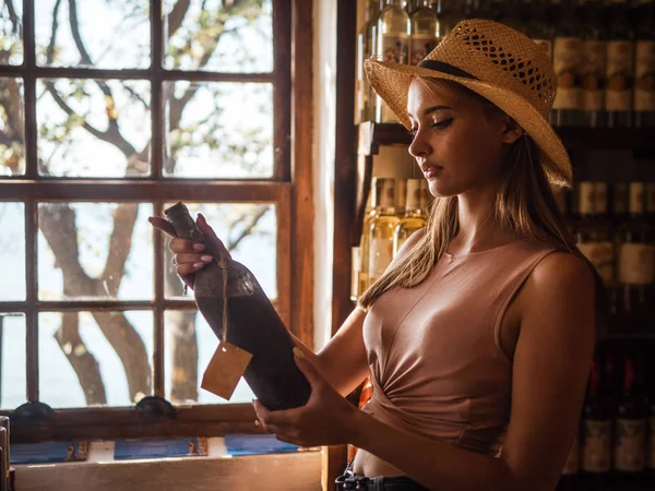 Giovane donna in una boutique di vino sceglie il vino — Foto Stock