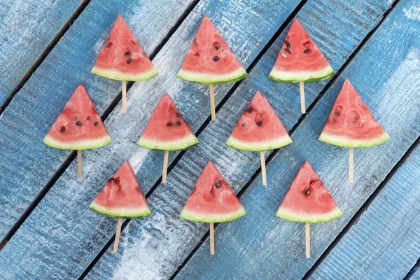 Triangulära skivor av vattenmelon på en blå trä bakgrund. — Stockfoto