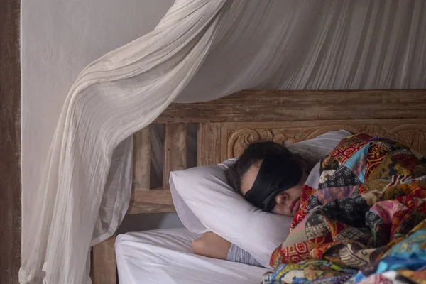 Жінка спить у масці для сну під клаптиковою ковдрою . — стокове фото