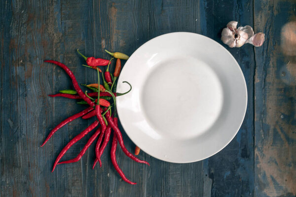 white plate on the background of old boards, wood, with chili pepper, spices