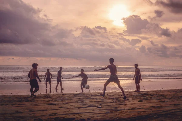 Indonesia, Pasut, 1 de febrero de 2019. Los hombres juegan al fútbol en la playa al atardecer — Foto de Stock