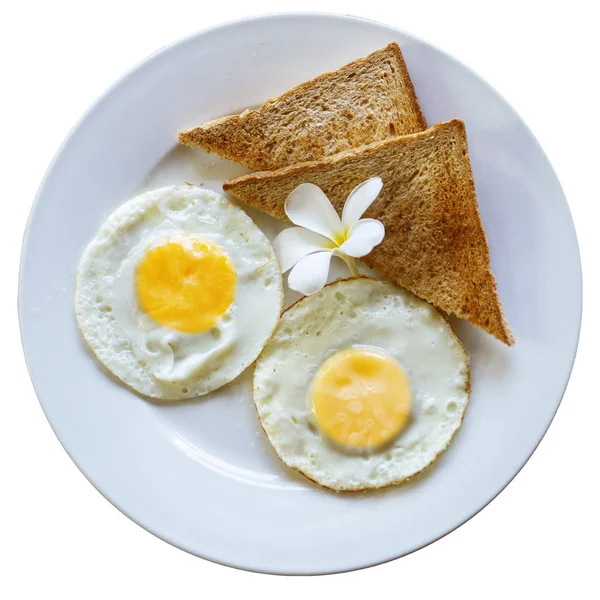 Τηγανητά αυγά με τοστ σε λευκό πιάτο διακοσμημένο με ένα τροπικό λουλούδι. Νόστιμο, υγιεινό πρωινό σε ένα τροπικό θέρετρο. Απομονωμένες — Φωτογραφία Αρχείου