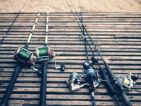 Cañas de pescar, cañas giratorias con hilo de pescar sobre un fondo de madera a la luz de la mañana. Pesca . — Foto de Stock