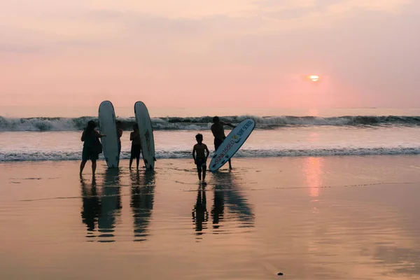 Indonesia, Bali, 4 de abril de 2019 Una familia en una playa de tablas de surf es fotografiada al atardecer junto al mar — Foto de Stock