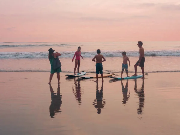 Indonesia, Bali, 4 de abril de 2019 Una familia en una playa de tablas de surf es fotografiada al atardecer junto al mar — Foto de Stock