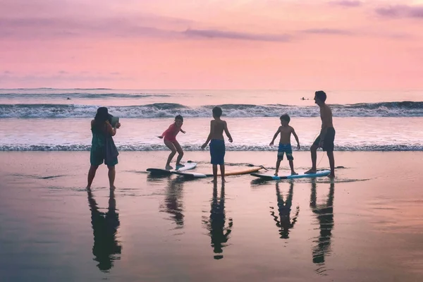 Indonesia, Bali, April 4, 2019 A family on a surfboard beach is photographed at sunset by the sea — Stock Photo, Image