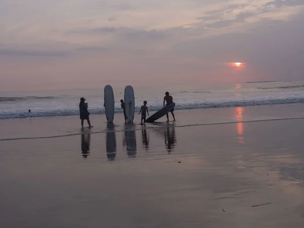 Indonesia, Bali, 4 de abril de 2019 Una familia en una playa de tablas de surf es fotografiada al atardecer junto al mar — Foto de Stock