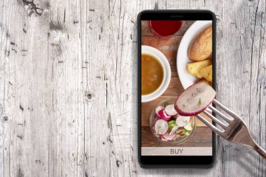 Akıllı telefonunuzdan sipariş ve gıda teslimatı. Ahşap arka planda akıllı telefon