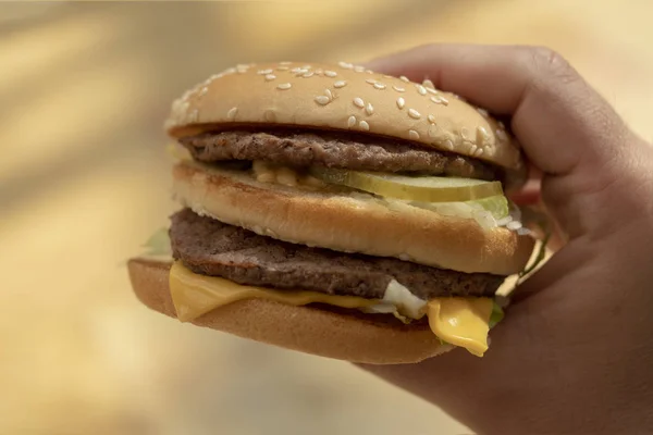 Burger w dłoni z bliska — Zdjęcie stockowe