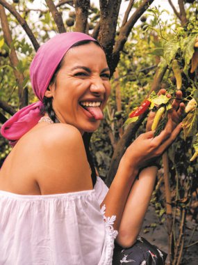 Çiftlikteki genç kadın bahçede acı biber tadıyor.