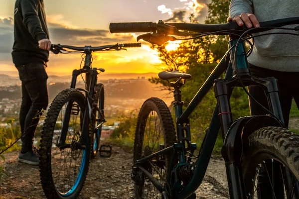 A couple of mountain bikes at sunset on the background of the city. Traveling on mountain bike in nature. Cycling holiday. — Stock Photo, Image