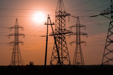 Enerji sektörü ülke. Yüksek gerilim direkleri-destek batan güneşin ışınları ışığında.