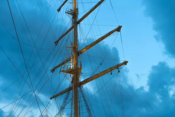 The mast of a large sailing ship against the background of the evening sky.