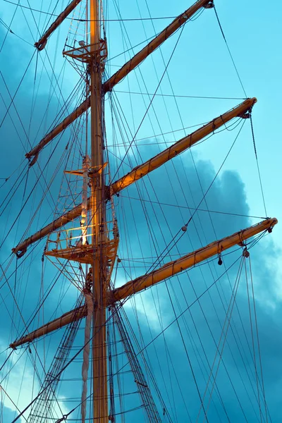 The mast of a large sailing ship against the background of the heaven, vertical photo.