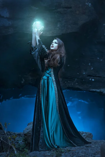 Ведьма с волшебным шаром в руках вызывает духов — стоковое фото