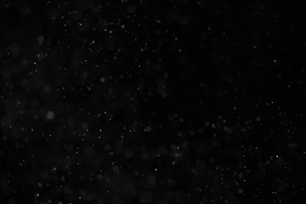 Абстрактная настоящая пыль, плавающая на черном фоне — стоковое фото