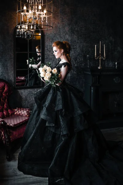 Attractive woman in black dress in medieval interior — Stock Photo, Image