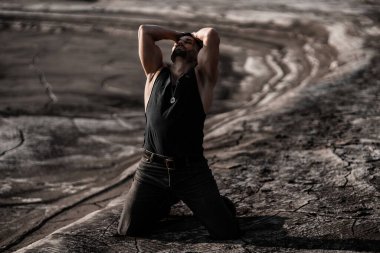 Siyah kumda bronzlaşmış çekici bir adam.