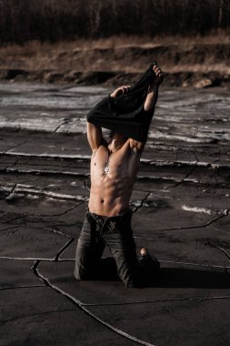 Siyah kumda bronzlaşmış çekici bir adam.