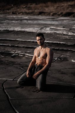 Siyah kumda bronzlaşmış çekici bir adam.