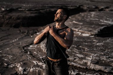 Siyah kumda bronzlaşmış çekici bir adam.