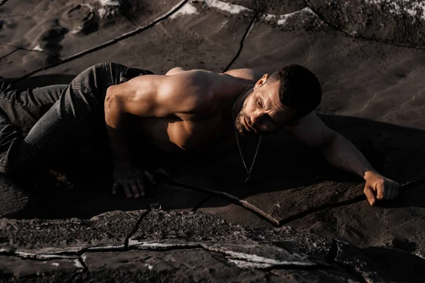 Attractive tanned man on the black sand