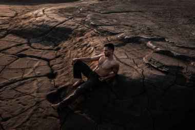 Siyah kumda bronzlaşmış çekici bir adam.