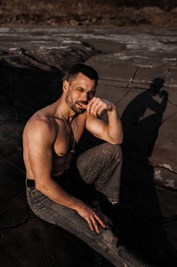 Siyah kumda bronzlaşmış çekici bir adam.