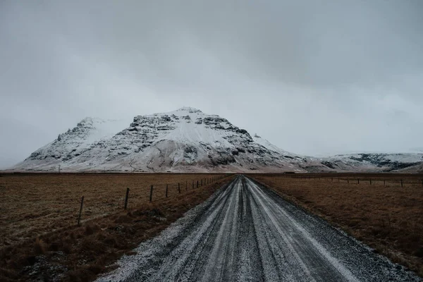 Uma Estrada Coberta Neve Islândia Que Leva Algumas Montanhas — Fotografia de Stock