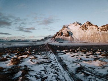 Bir dağ bir kar üzerinden doğru giden bir yol Stokksnes, İzlanda manzara kaplı. Fotoğraf bir dron kullanarak alınır.