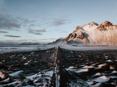 Bir dağ bir kar üzerinden doğru giden bir yol Stokksnes, İzlanda manzara kaplı. Fotoğraf bir dron kullanarak alınır.