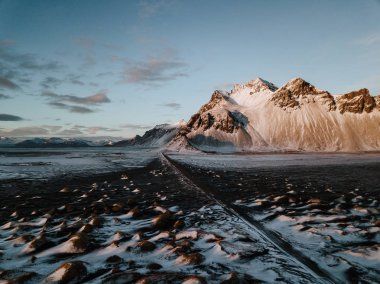 Bir dağ bir kar üzerinden doğru giden bir yol Stokksnes, İzlanda manzara kaplı. Fotoğraf bir dron kullanarak alınır.