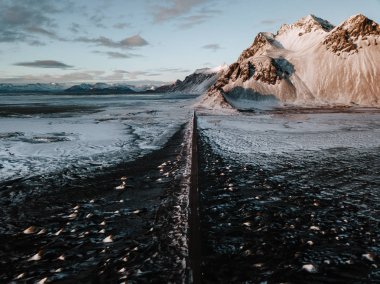 Bir dağ bir kar üzerinden doğru giden bir yol Stokksnes, İzlanda manzara kaplı. Fotoğraf bir dron kullanarak alınır.
