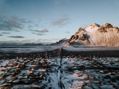 Bir dağ bir kar üzerinden doğru giden bir yol Stokksnes, İzlanda manzara kaplı. Fotoğraf bir dron kullanarak alınır.
