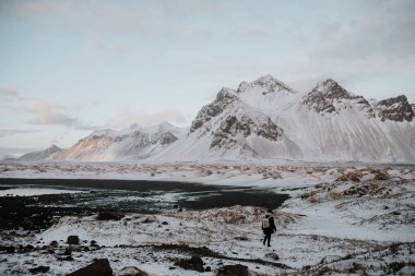 Kar kaplı alanın doğru Stokksnes, İzlanda bir siyah kum Plajı üzerinde yürüyen bir insan.